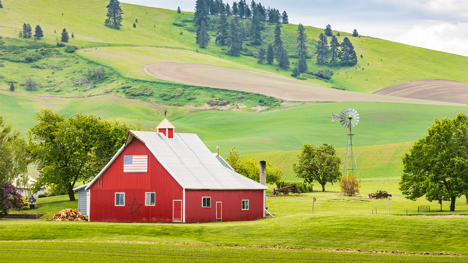 Red barn next to grassy hill